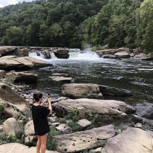woman taking a photo of waterfalls