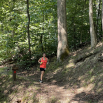 woman in red shirt running on a trail in the woods