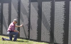 man kneeling before the Vietnam Traveling Memorial Wall