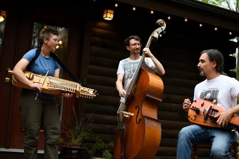 3 people standing outside holding string instruments