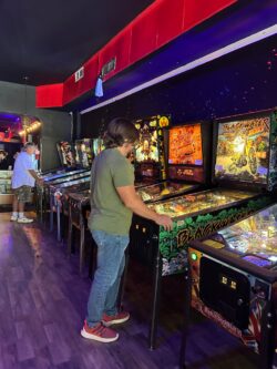 two men playing pin ball at an arcade