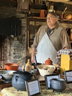 man dressed in 18th century clothes demonstrating hearth cooking