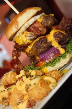 large hamburger with tater tots covered in cheese