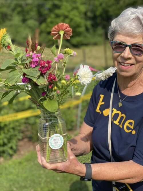 Photo of woman holding a jar of flowers